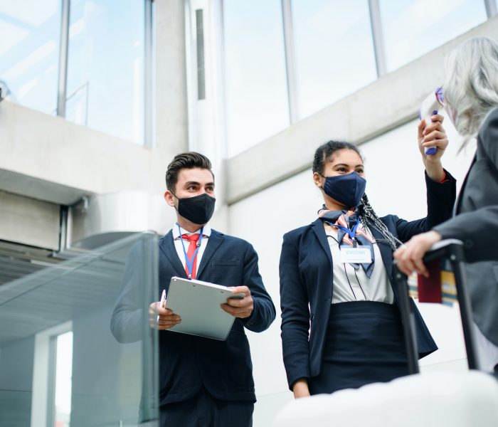 Senior woman in airport terminal, coronavirus, travel, measuring temperature and new normal